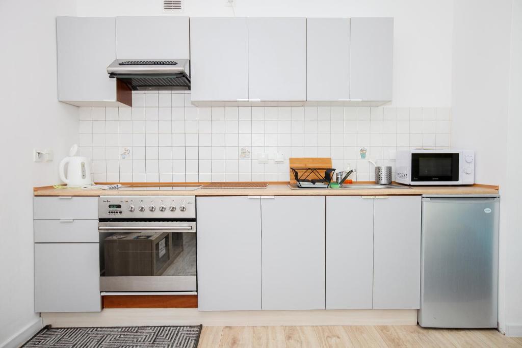 una cucina bianca con armadi bianchi e forno a microonde di Green Kabaty Apartment 3 a Varsavia