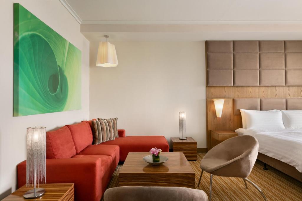 a living room with a red couch and a bed at Traders Hotel, Abu Dhabi in Abu Dhabi