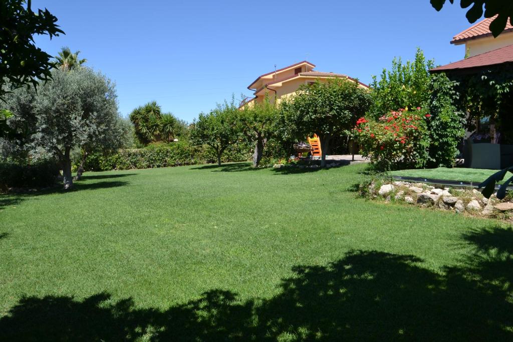 un cortile con prato verde e alberi e una casa di B&B Due Fontane a Caltanissetta