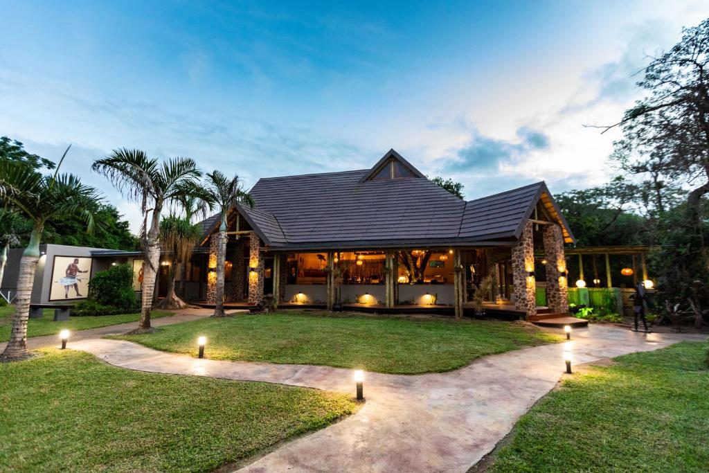 a house with a black roof and a yard at Gooderson DumaZulu Lodge in Hluhluwe