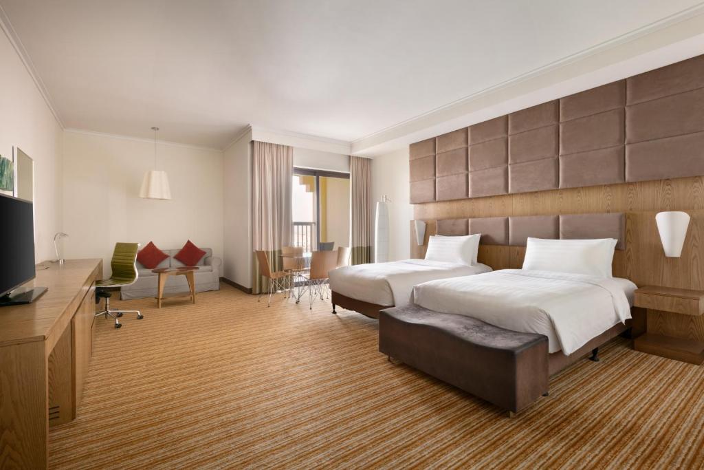 a large hotel room with two beds and a desk at Traders Hotel, Abu Dhabi in Abu Dhabi