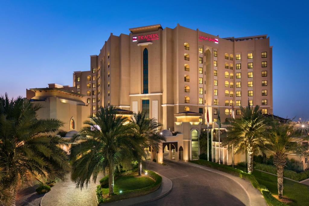 a hotel with palm trees in front of a building at Traders Hotel, Abu Dhabi in Abu Dhabi