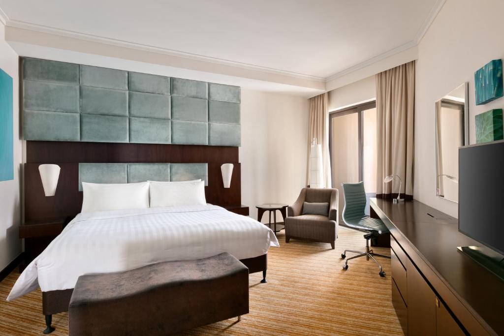 a hotel room with a large bed and a desk at Traders Hotel, Abu Dhabi in Abu Dhabi