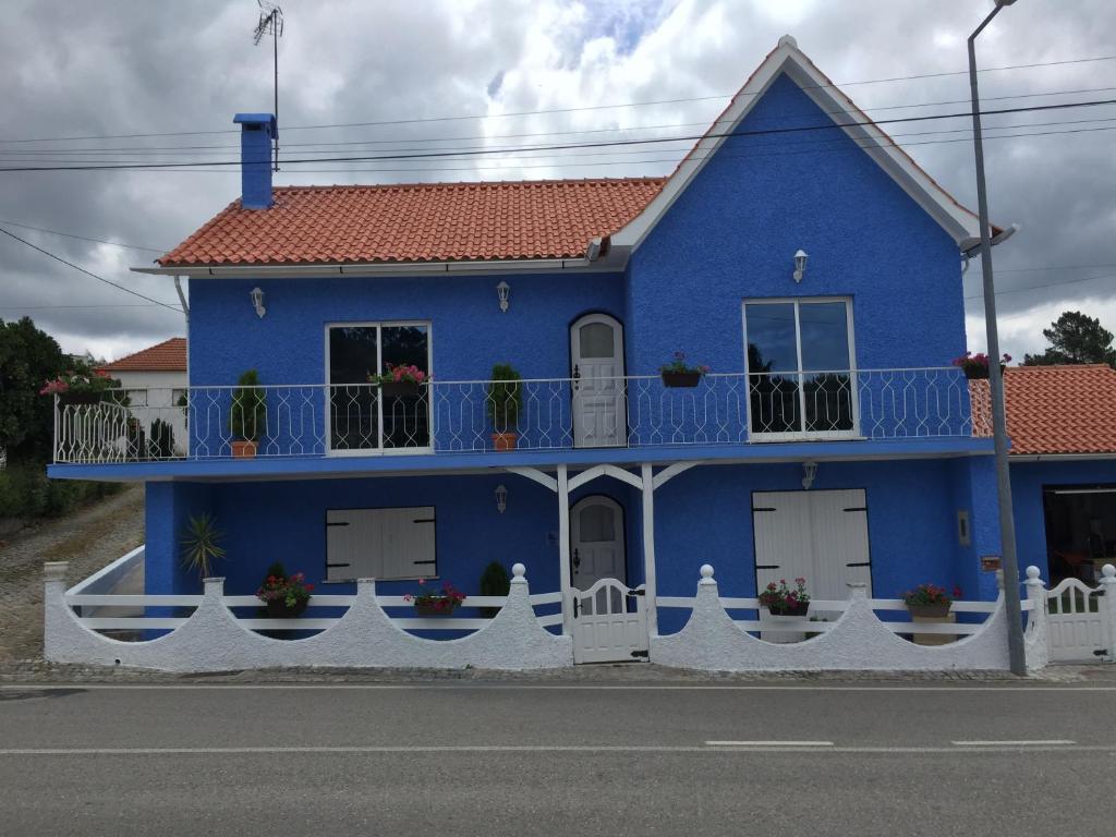 uma casa azul com uma cerca branca em frente em Casa De Newsham em Cabaços