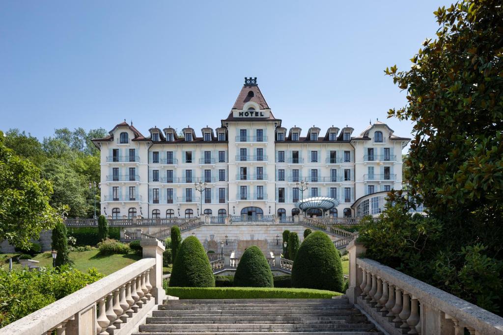a large white building with stairs in front of it at Le Palace De Menthon in Menthon-Saint-Bernard