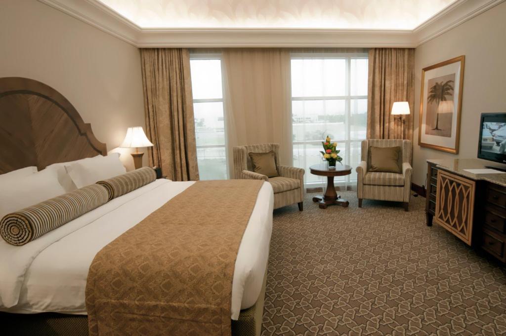 a hotel room with a large bed and a television at Ayla Hotel in Al Ain