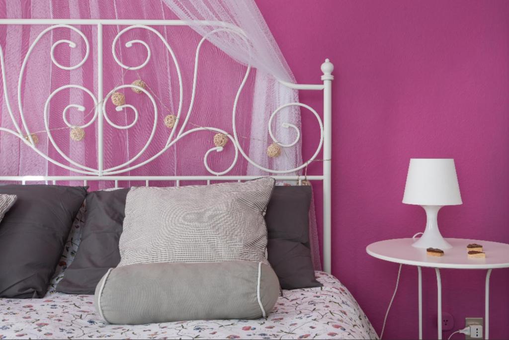 een slaapkamer met een wit bed en een roze muur bij Casa Rocca d'Api in Zafferana Etnea