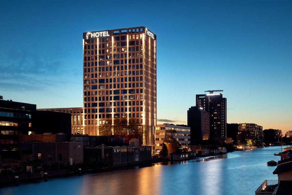 een hoog gebouw aan de kant van een rivier bij Van der Valk Hotel Amsterdam - Amstel in Amsterdam