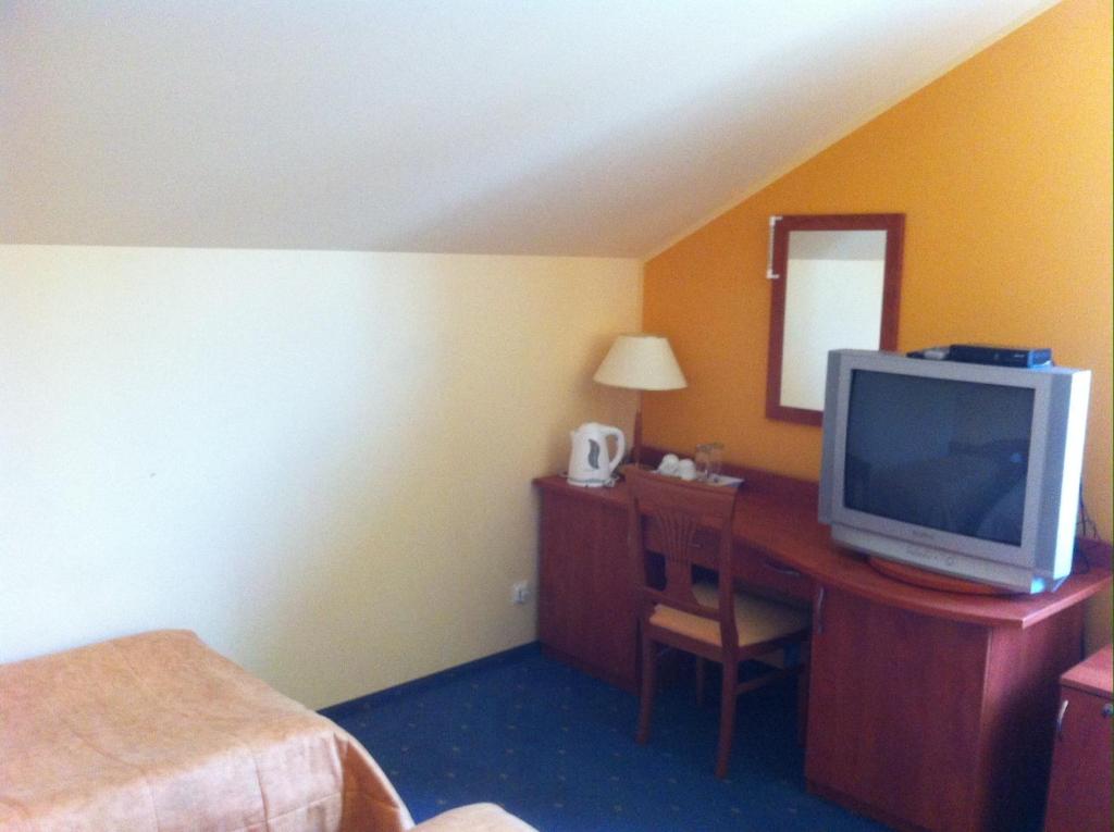 1 dormitorio con escritorio, TV y espejo en Guest House Guba en Molėtai