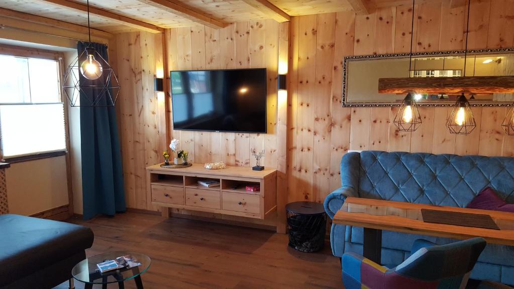 sala de estar con sofá azul y TV en Ferienwohnung Zirbenduft en Inzell