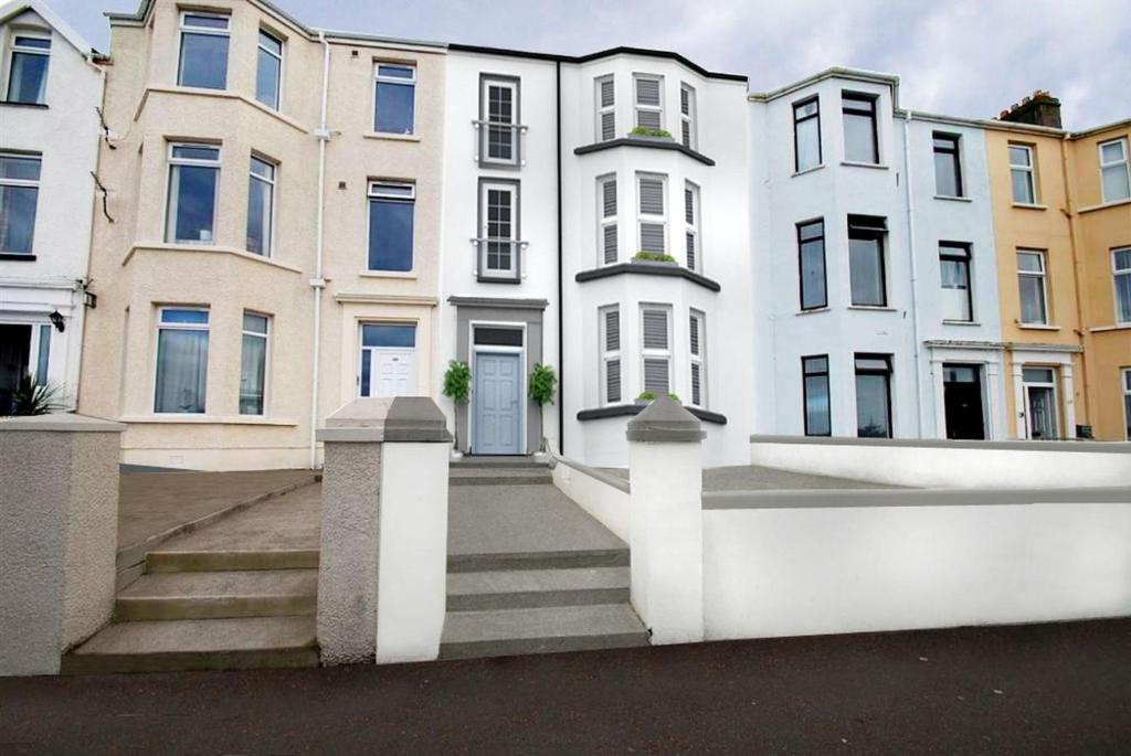 a row of white buildings with stairs in front at 107 Eglinton Street in Portrush