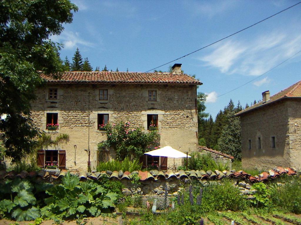 stary kamienny budynek z parasolem w ogrodzie w obiekcie La Fontaine des Thiolles w mieście Saint-Germain-lʼHerm