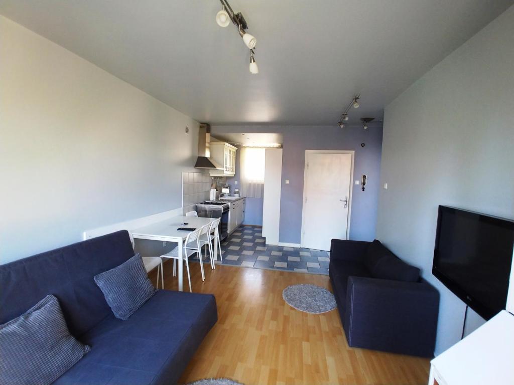 a living room with a blue couch and a kitchen at Apartament Saski in Warsaw