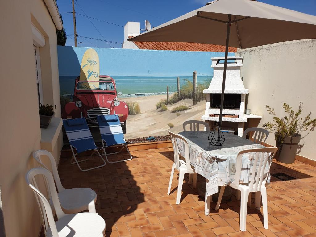 un patio avec une table, des chaises et un parasol dans l'établissement petite maison les sables d'olonne, à Les Sables-dʼOlonne