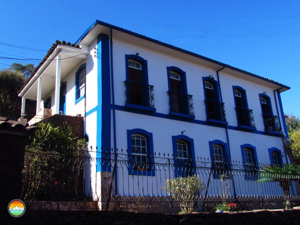 a white house with black windows and a fence at Buena Vista Hostel in Ouro Preto