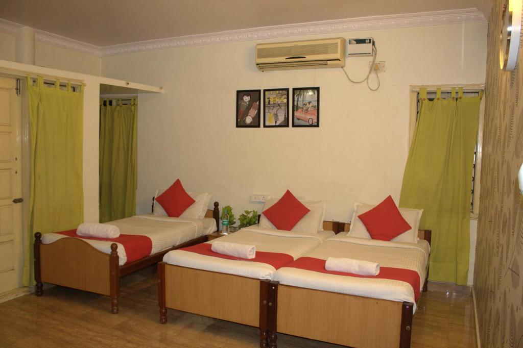 two beds in a room with green curtains at Nachis BNB in Bangalore