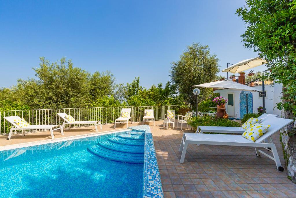 a pool with chairs and a bench next to a house at Villa Sorrento Flats in Sorrento