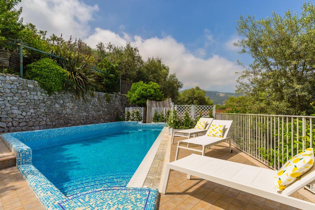 - une piscine avec 2 chaises et un banc à côté dans l'établissement Villa Sorrento Flats, à Sorrente