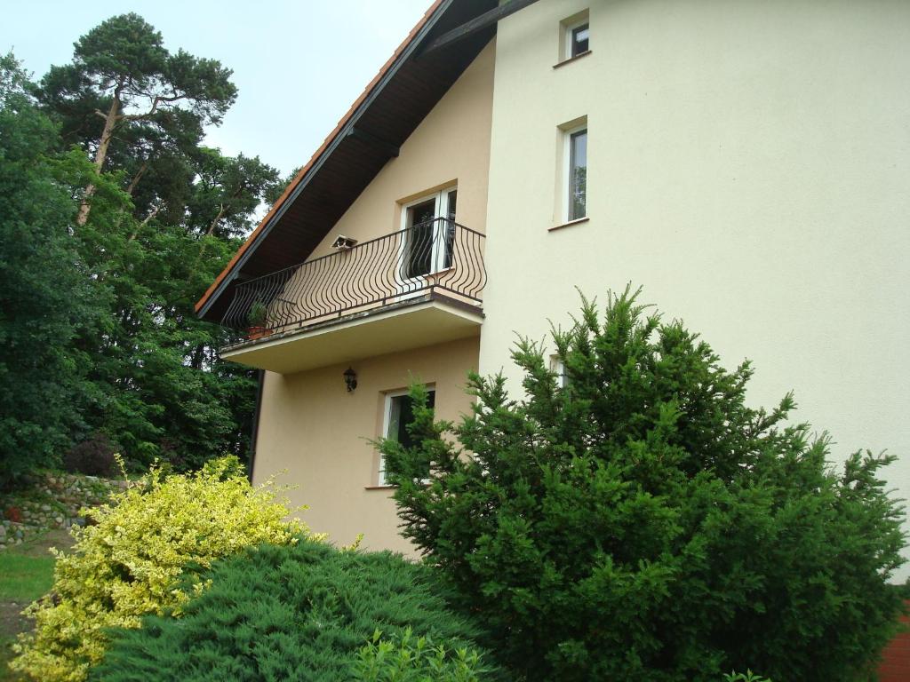 biały budynek z balkonem i krzakami w obiekcie W Starym Sadzie w mieście Owińska