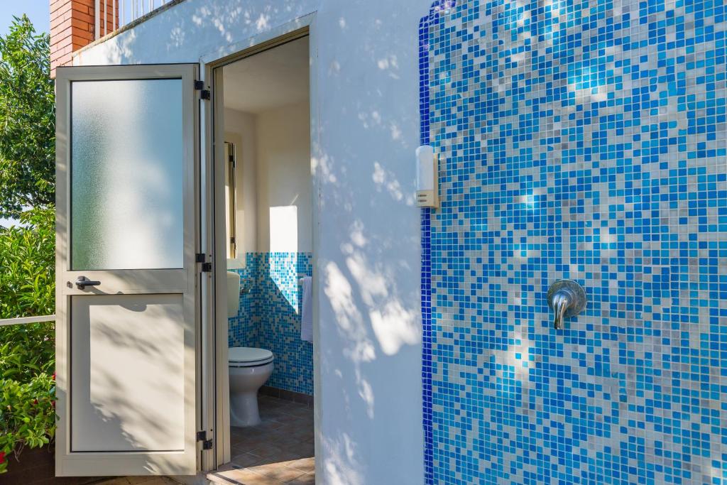 La salle de bains est pourvue de toilettes et d'un mur carrelé bleu. dans l'établissement Villa Sorrento Flats, à Sorrente