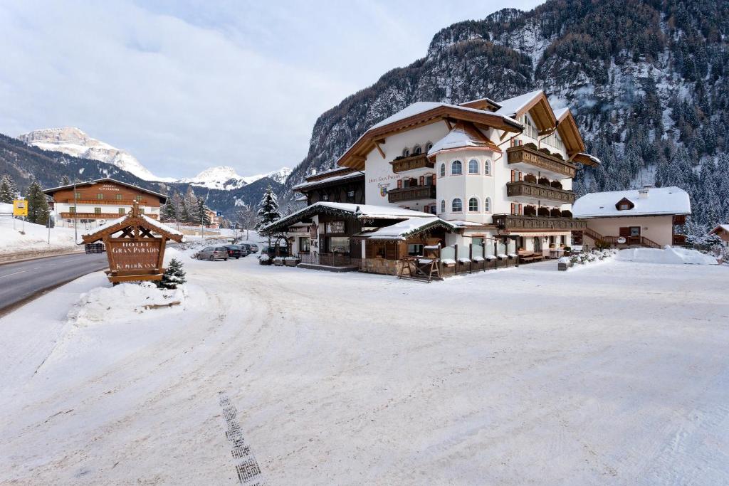 uma estrada coberta de neve em frente a um alojamento de turismo selvagem em Hotel Gran Paradis em Campitello di Fassa