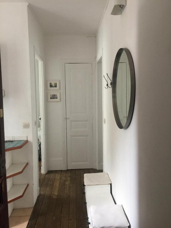 a white hallway with a mirror and a stool at Joli 2 pièces # Paris 14eme in Paris