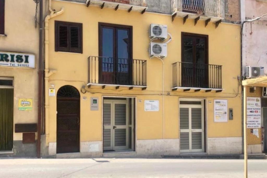 a yellow building with windows and balconies on a street at “La Rampa” Affitti Brevi - Racalmuto (AG) Sicilia in Racalmuto