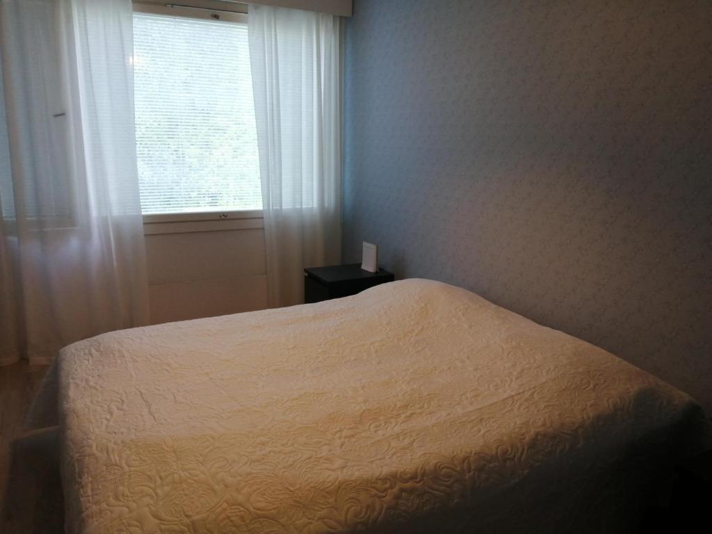 1 dormitorio con cama blanca y ventana en Laajavuori Apartment, en Jyväskylä
