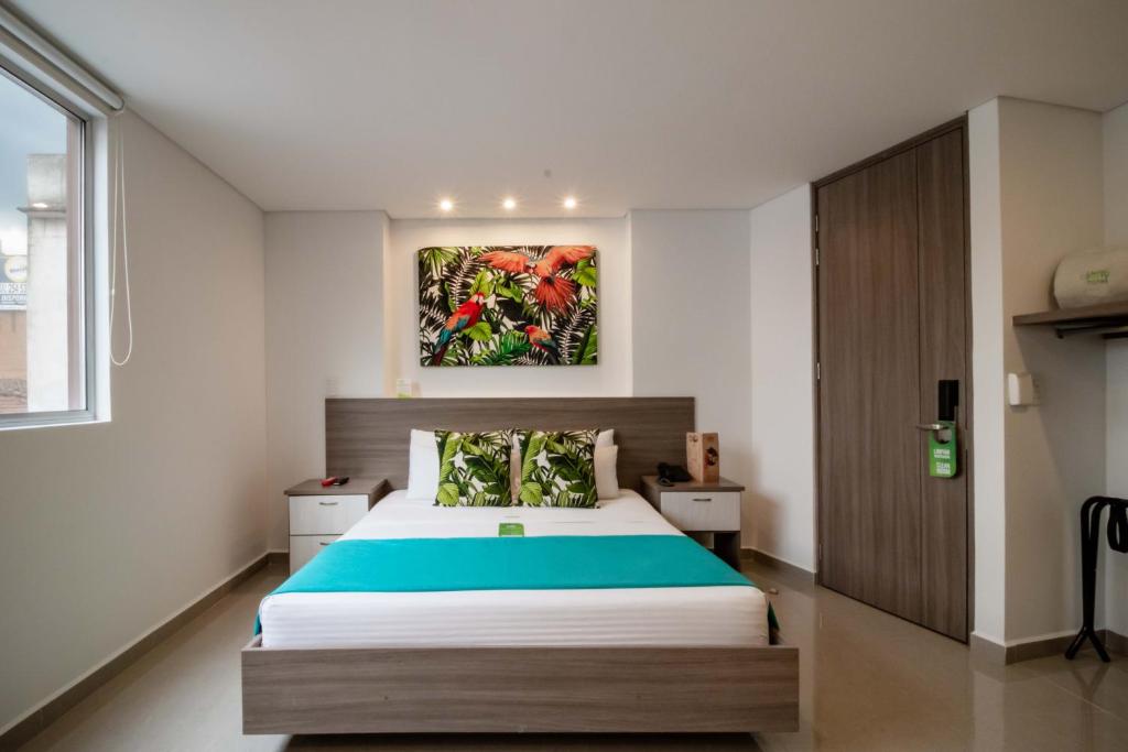 1 dormitorio con 1 cama y una pintura en la pared en Lleras Green Hotel, en Medellín