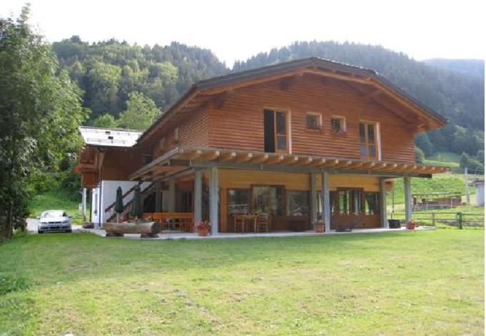 a large wooden house with a grass field in front of it at La Vecchia Latteria in Pontebba