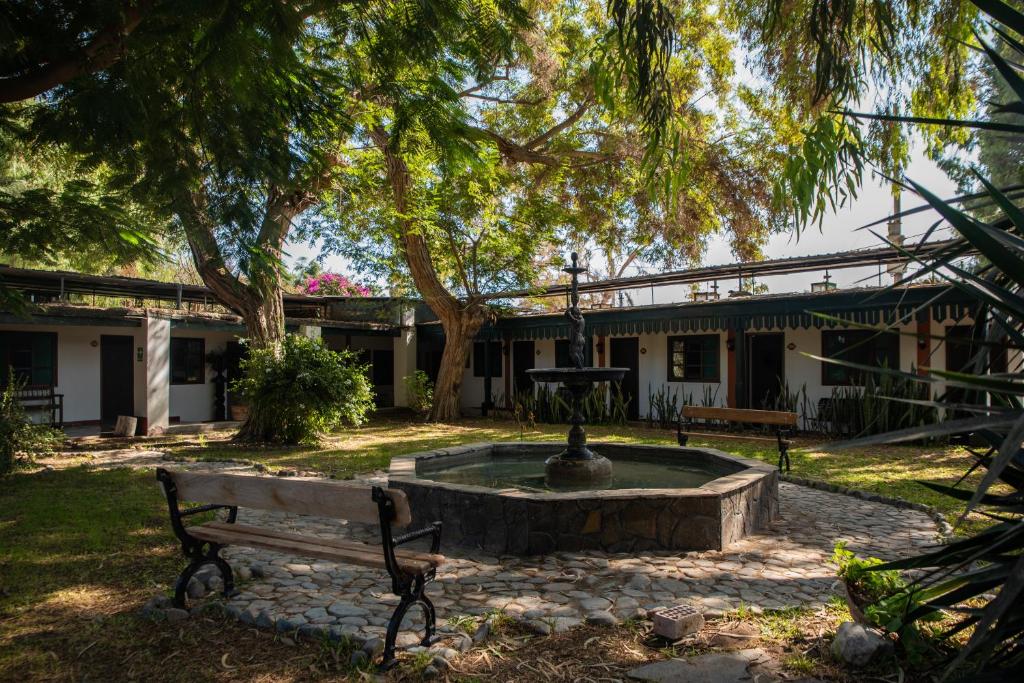 a park bench with a fountain in front of a building at Hotel Majoro in Nazca