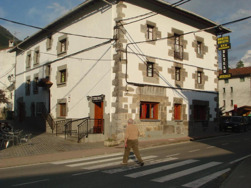 Ein Mann überquert eine Straße vor einem Gebäude in der Unterkunft Hostal Betelu in Betelu