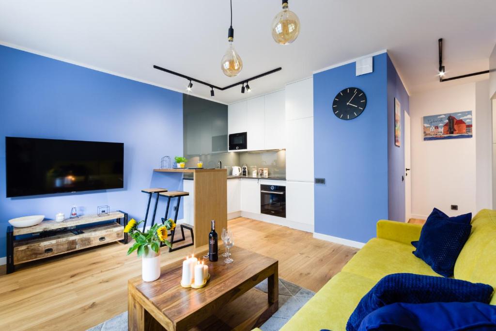 ein Wohnzimmer mit einem gelben Sofa und einem Tisch in der Unterkunft Motlava Gdansk Apartment in Danzig