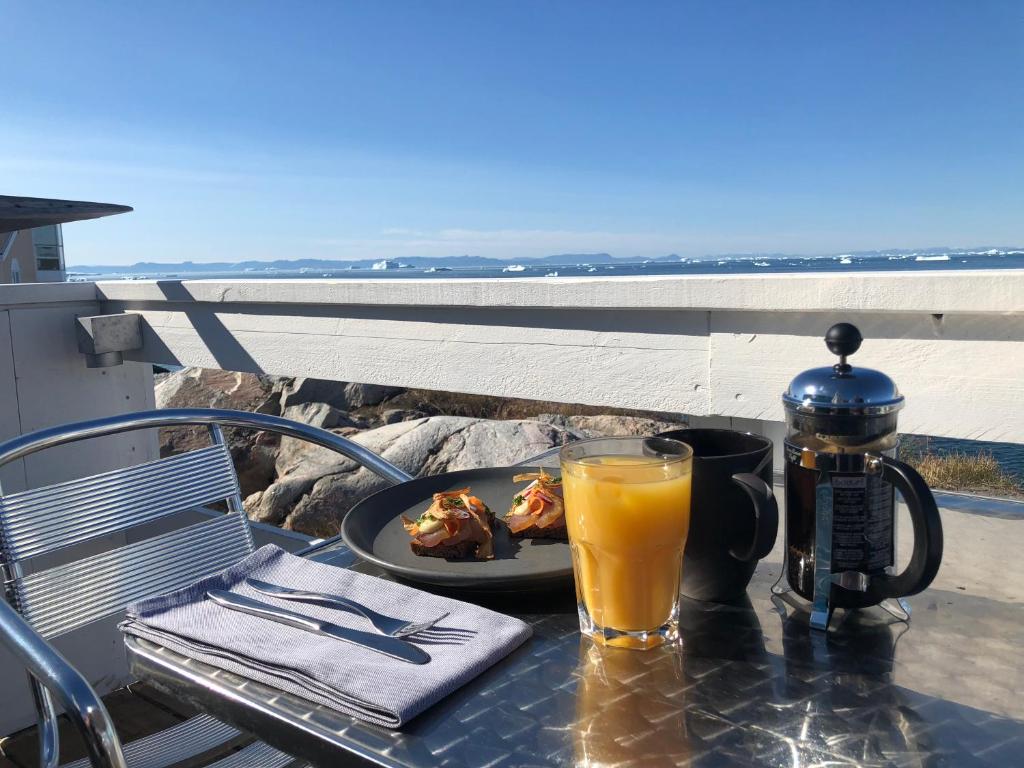 a table with a plate of food and a glass of orange juice at Hotel Icefiord in Ilulissat