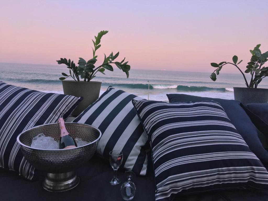 a table with a bottle of wine and pillows on the beach at Escape to a Seaside Sanctuary - vayKZN Umdloti in Umdloti