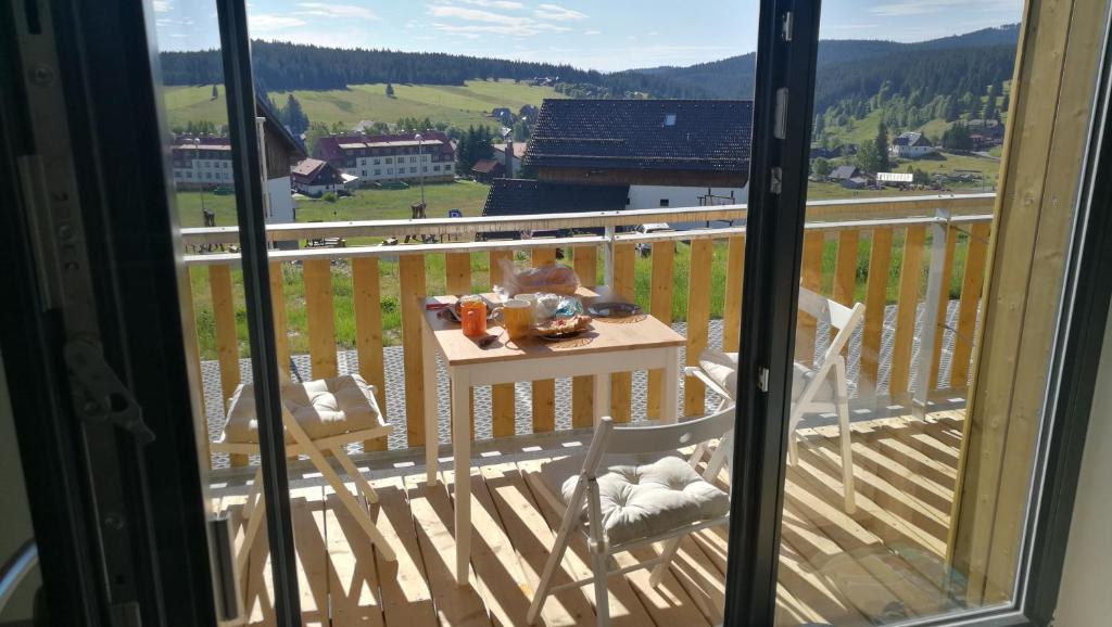 un balcone con tavolo e sedie su una terrazza di apartmán Pod Lapkou a Kvilda
