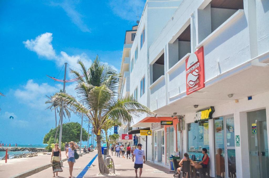 a group of people walking down a sidewalk next to a beach at Portobelo Boulevard in San Andrés