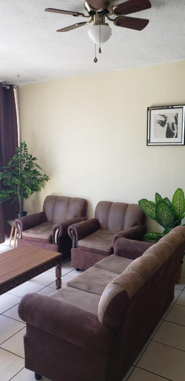 a living room with brown leather couches and a ceiling at Executive Apartment Guatemala City in Guatemala
