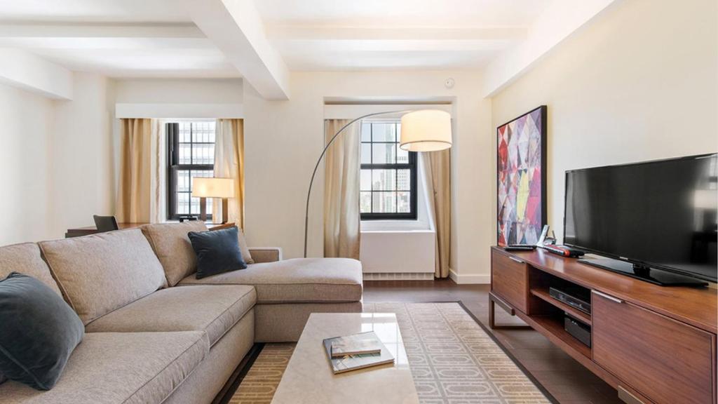 a living room with a couch and a flat screen tv at The Beekman Tower, Trademark Collection by Wyndham in New York