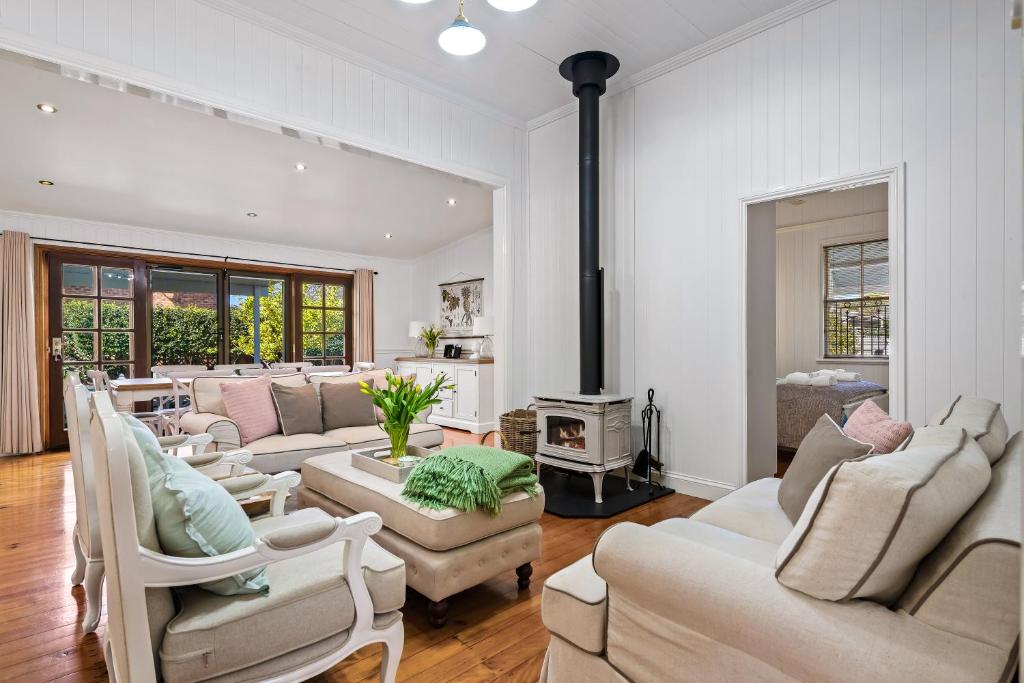 a living room with white furniture and a fireplace at Frangipani House in Toowoomba