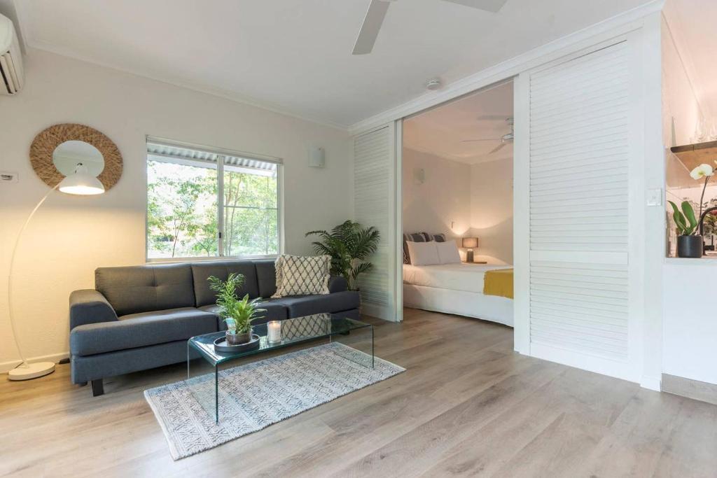 a living room with a couch and a bed at Ocean Palms Apartments in Port Douglas