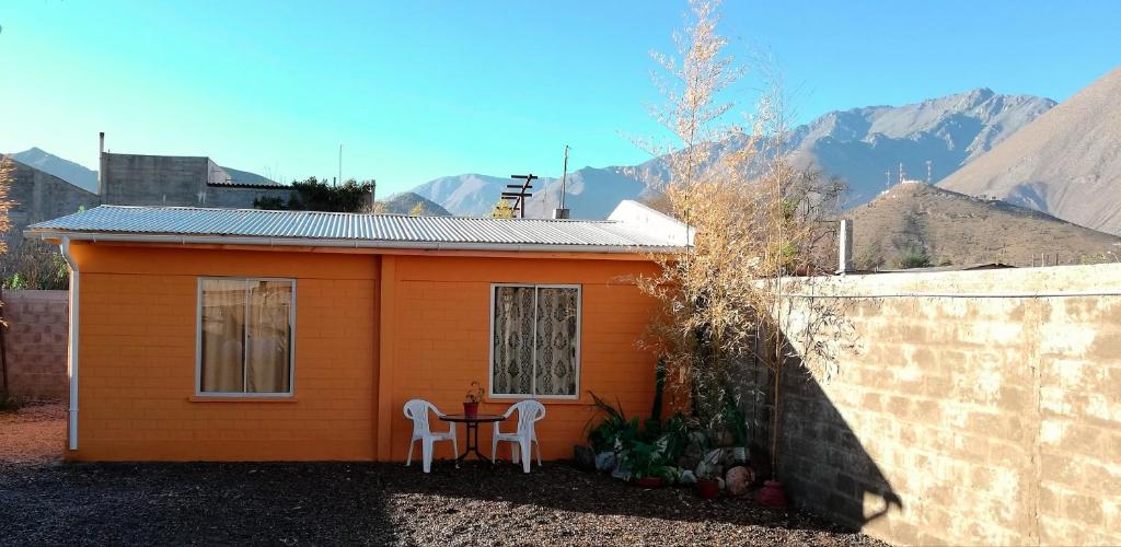 mały pomarańczowy dom z dwoma krzesłami i stołem w obiekcie Cabaña Vicuña w mieście Vicuña