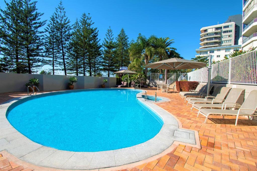 a large swimming pool with chairs and an umbrella at Cashelmara Beachfront Apartments in Gold Coast