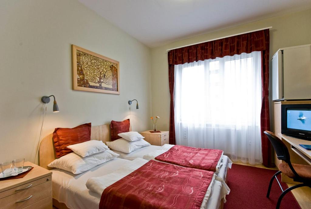 a bedroom with a bed and a desk and a television at Hotel Kerpely in Dunaújváros