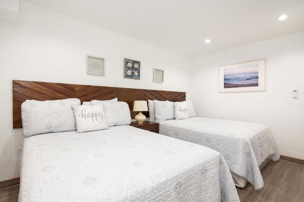 聖佩德羅的住宿－La Casa de Paz Hotel，一间卧室配有两张带白色床单的床