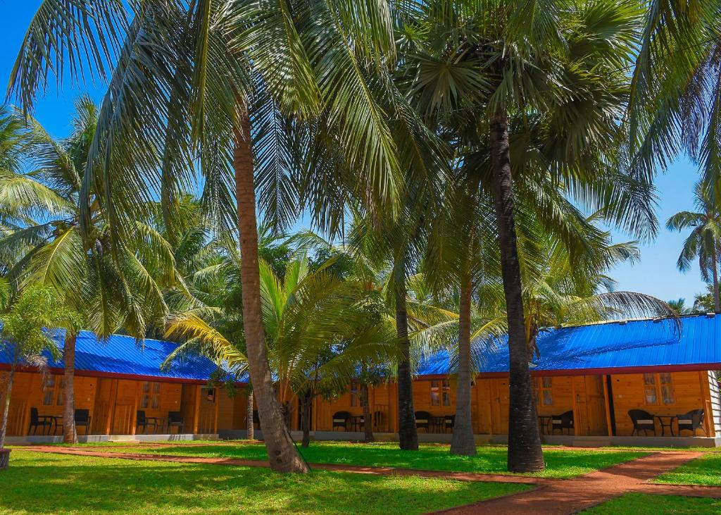 a building with palm trees in front of it at Trinco Relax Hut in Trincomalee