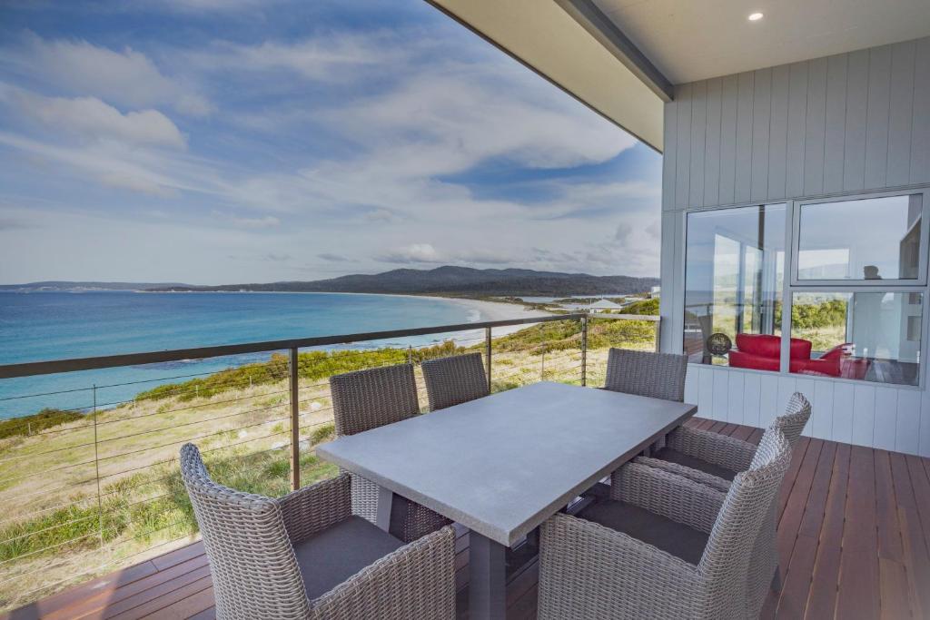 a table and chairs on a balcony with a view of the ocean at Tranquility Bay of Fires in Binalong Bay