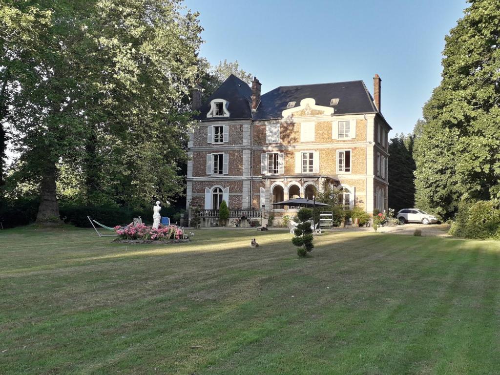 Château de la Bucaille - entier في Aincourt: منزل كبير أمامه ميدان عشبي كبير