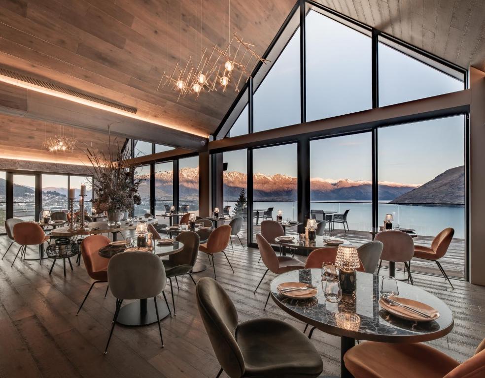 a restaurant with tables and chairs and large windows at Kamana Lakehouse in Queenstown