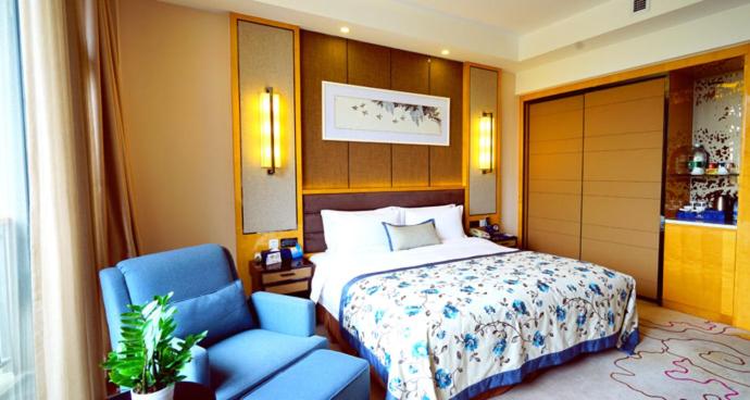 um quarto com uma cama e uma cadeira azul em Beijing Yun-zen Jinling Lotus Hotel em Pequim